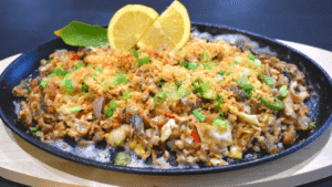 Bangus Sisig is a Filipino dish made from milkfish (bangus) that has been deboned, flaked, and cooked with various ingredients such as onions, garlic, chili peppers, and mayonnaise. It is typically served on a sizzling plate and topped with a raw egg for added creaminess.