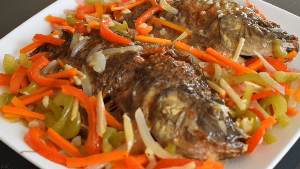 Escabeche is a popular Filipino dish that consists of fried fish or meat, topped with a sweet and sour sauce made from vinegar, soy sauce, sugar, and various spices. This dish has Spanish origins and the name "escabeche" comes from the Spanish word "escabechar", which means to marinate in an acidic solution.