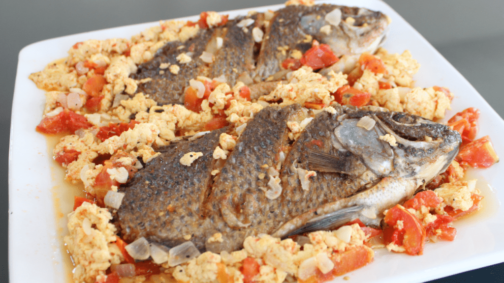 Sarciadong Tilapia is a Filipino dish made with fried tilapia fish that is smothered in a tangy tomato-based sauce. The sauce is typically made with tomato, onion, garlic, and vinegar or calamansi juice (a type of citrus fruit).