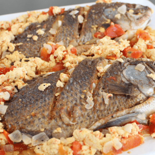 Sarciadong Tilapia is a Filipino dish made with fried tilapia fish that is smothered in a tangy tomato-based sauce. The sauce is typically made with tomato, onion, garlic, and vinegar or calamansi juice (a type of citrus fruit).