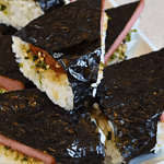 Spam musubi is a popular Hawaiian dish that has gained widespread popularity outside of Hawaii. It consists of grilled or fried spam, a canned meat product, served on top of sushi rice and wrapped in seaweed.