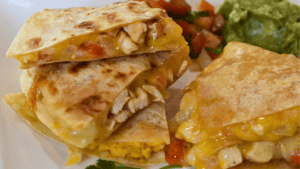 Chicken quesadilla is a mouth-watering Mexican dish. It consists of a tortilla filled with cooked chicken, melted cheese, and other delicious ingredients, then folded in half and toasted on a skillet until golden brown.