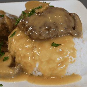 The Jollibee-Style Burger Steak with Mushroom Gravy is a popular Filipino fast-food dish that consists of crispy beef patties smothered in a rich and creamy mushroom gravy. It's served on top of steaming hot rice, making it a hearty and satisfying meal for any occasion.